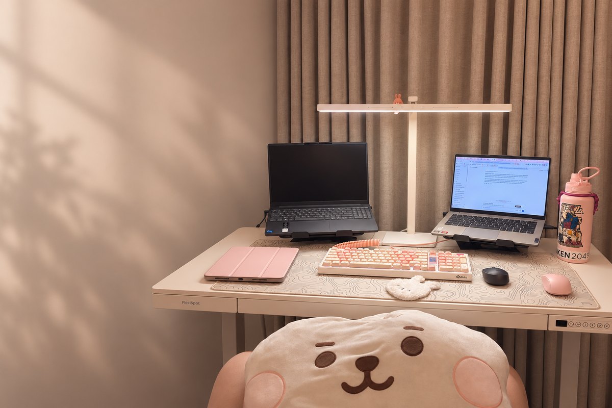 My desk in Makati: a warm, lamp-lit setup with a laptop, keyboard, and a few soft-pink bits and pieces.